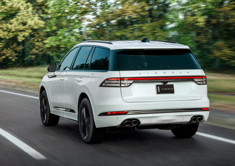 A white 2025 Lincoln Aviator® SUV is being driven away down a road lined with colorful trees. | White's Canyon Motors - Lincoln in Spearfish SD