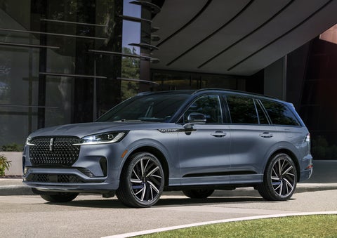 A gray 2025 Lincoln Aviator® SUV is parked outside a modern building showcasing the driver’s side of the vehicle. | White's Canyon Motors - Lincoln in Spearfish SD