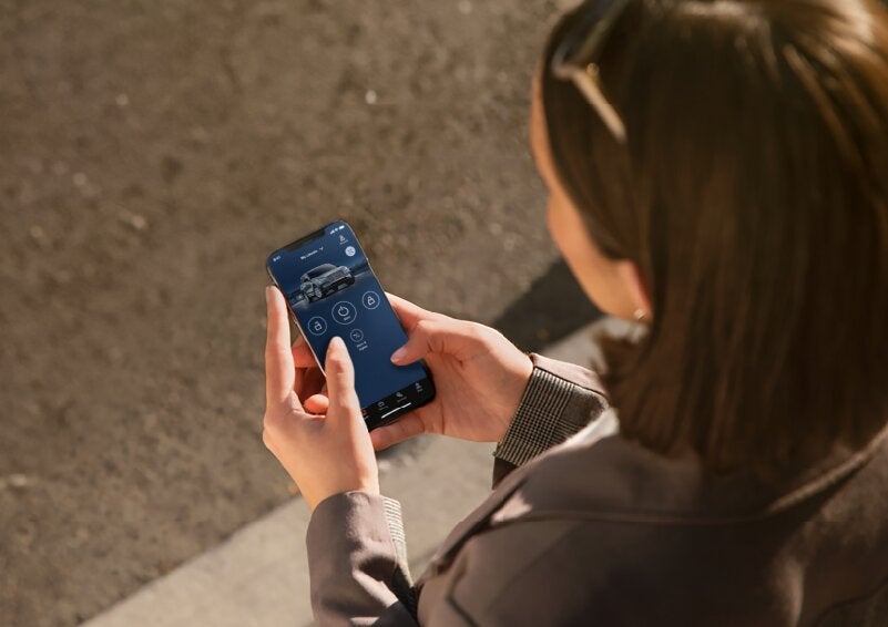A person is shown interacting with a smartphone to connect to a Lincoln vehicle via the Lincoln Way® App. | White's Canyon Motors - Lincoln in Spearfish SD