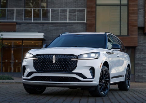 A 2026 Lincoln Aviator® Reserve model is shown with the available Jet Appearance Package parked near a restaurant. | White's Canyon Motors - Lincoln in Spearfish SD