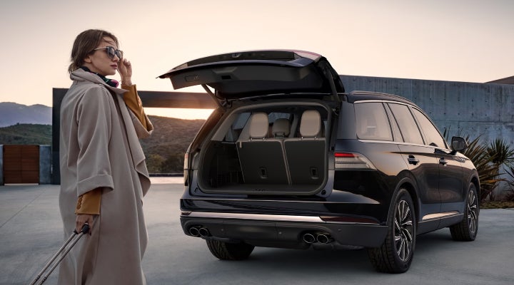A woman approaches a 2026 Lincoln Aviator® SUV with its rear liftgate open. | White's Canyon Motors - Lincoln in Spearfish SD