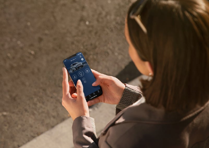A person is shown interacting with a smartphone to connect to a Lincoln vehicle via the Lincoln Way® app. | White's Canyon Motors - Lincoln in Spearfish SD