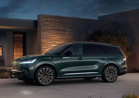 A green 2027 Lincoln Aviator® SUV is parked outside a contemporary home. | White's Canyon Motors - Lincoln in Spearfish SD