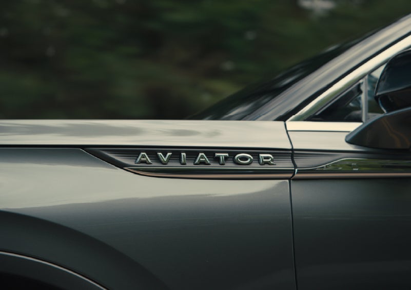 The driver’s side door and fender badging of a gray 2027 Lincoln Aviator® SUV are showcased. | White's Canyon Motors - Lincoln in Spearfish SD