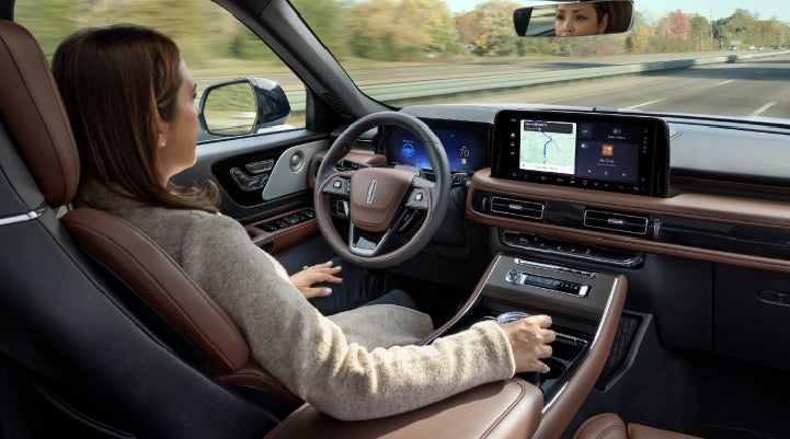 A 2027 Lincoln Aviator® SUV is being driven hands-free on a highway lined with trees. | White's Canyon Motors - Lincoln in Spearfish SD