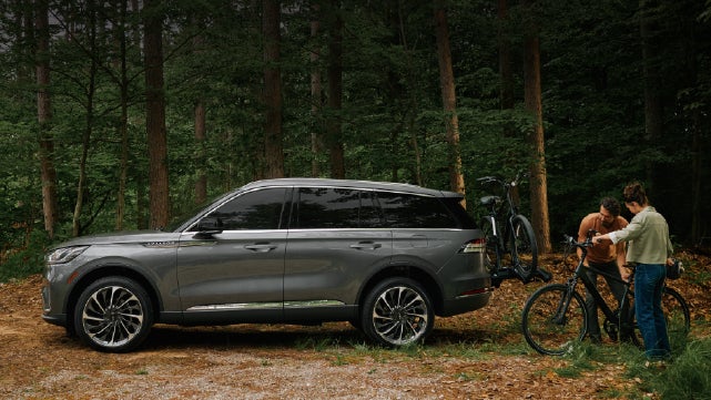 A father and son load e-bikes on a bike rack attached to a 2027 Lincoln Aviator® SUV. | White's Canyon Motors - Lincoln in Spearfish SD