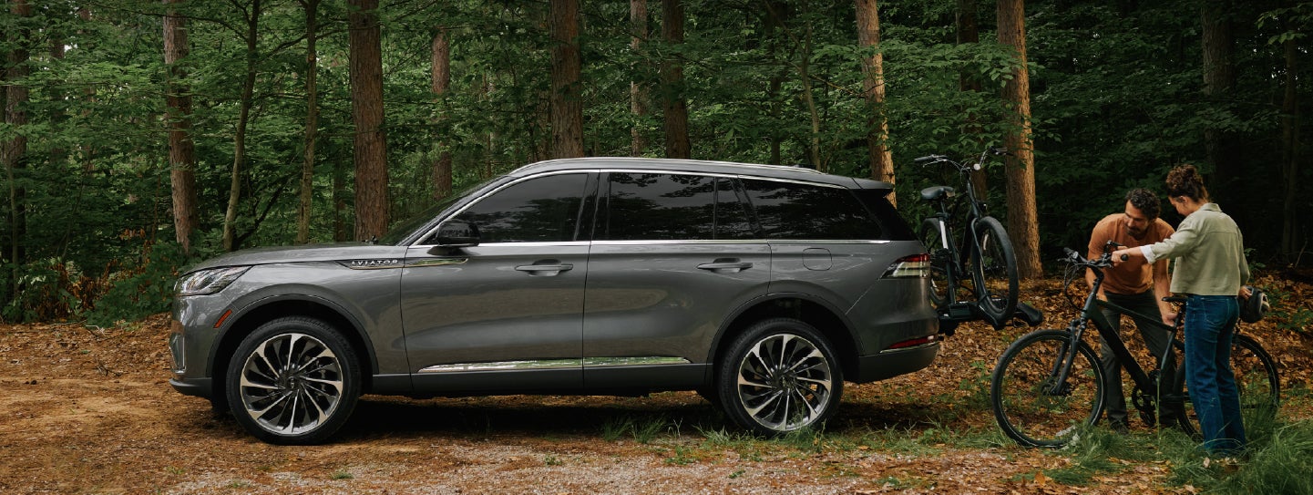 A father and son load e-bikes on a bike rack attached to a 2027 Lincoln Aviator® SUV. | White's Canyon Motors - Lincoln in Spearfish SD