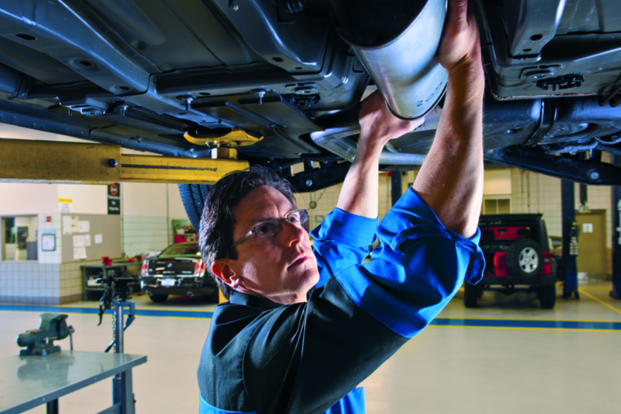 Technician repairing vehicle underside